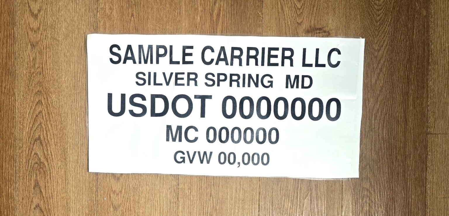 Actual sample truck door lettering on its white backing sheet, with placeholder carrier and USDOT details.